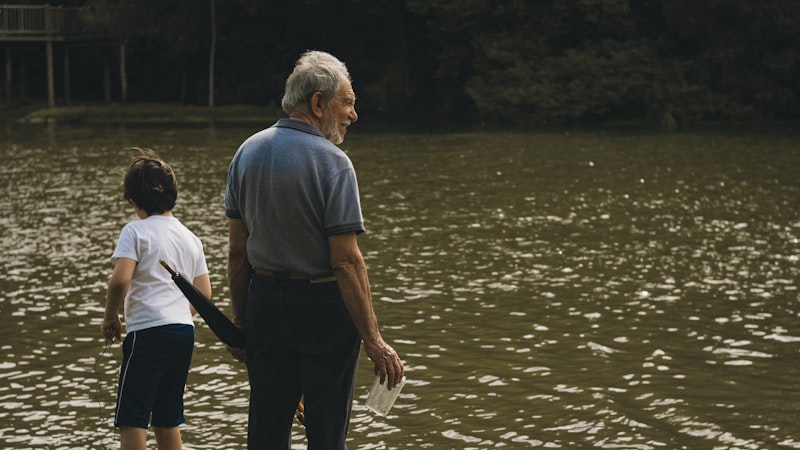Grandfather and grandson standing together by a lake